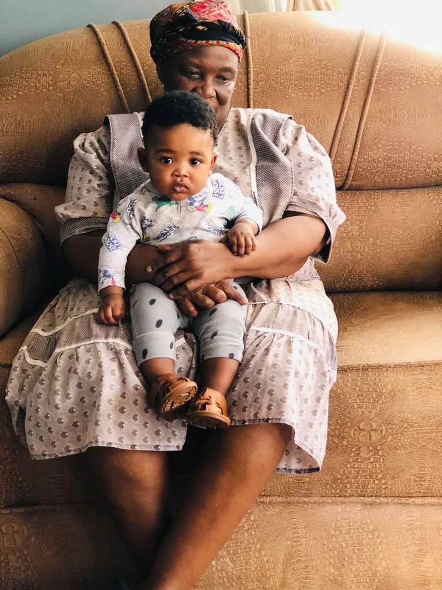A grandmother holding her grandchild on the couch at home