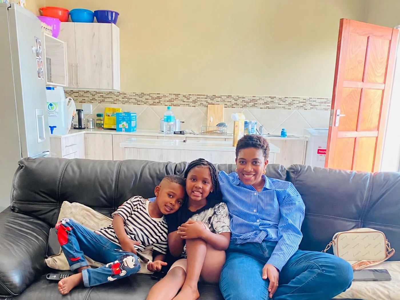 A real Elite Traders Lounge family — a mother relaxing at home with her two children on the couch